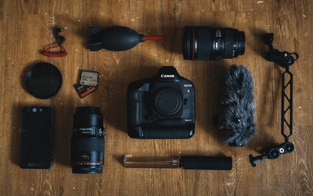 Flat lay of filmmaking equipment including a mirrorless camera, lenses, memory cards and a shotgun microphone